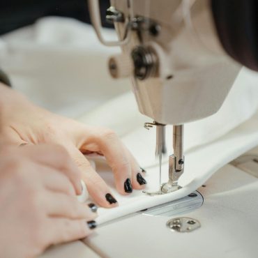 pexels photo 4622206 4622206 Detailed view of a sewing machine stitching fabric with visible hands, nails painted black.